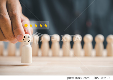 Business hiring and recruitment selection. Hand choosing a wooden figure as a star employee from the group. HR Management ensures success through teamwork and effective leadership. 105109302