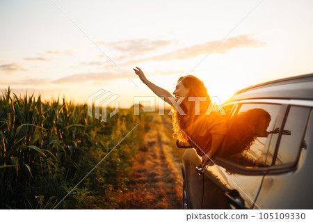 Happy woman outstretches her arms while sticking out car window. Lifestyle, travel, tourism, nature. Happy woman outstretches her arms while sticking out car window. Lifestyle, travel, tourism, nature. 105109330