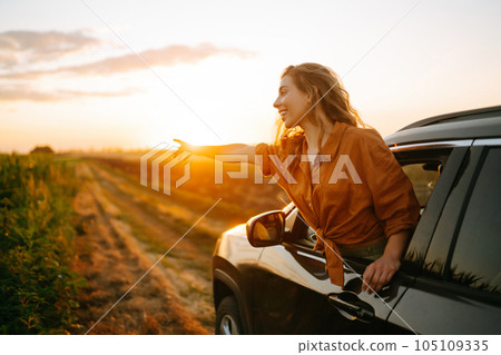 Happy woman outstretches her arms while sticking out car window. Lifestyle, travel, tourism, nature. Happy woman outstretches her arms while sticking out car window. Lifestyle, travel, tourism, nature. 105109335
