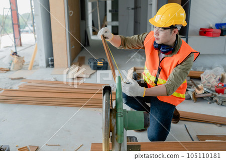 Structural worker dressed in safety gear and hard hat doing construction and using circular saw to work Structural worker dressed in safety gear and hard hat doing construction and using circular saw to work 105110181