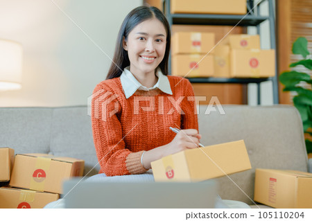 Starting small business entrepreneur of independent young Asian woman online seller is using computer and taking orders to pack products for delivery to customers. SME delivery concept. Starting small business entrepreneur of independent young Asian woman online seller is using computer and taking orders to pack products for delivery to customers. SME delivery concept. 105110204