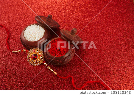 Raksha Bandhan. Rakhi string, Rice Grains and Kumkum on red background. Raksha Bandhan. Rakhi string, Rice Grains and Kumkum on red background. 105110348