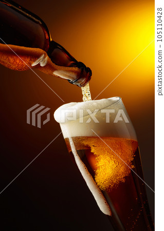 Pouring beer into a tall glass. 105110428