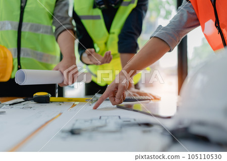 multi ethnic engineer brainstorming and measuring for cost estimating on paperworks and floor plan drawings about design architectural and engineering for houses and buildings. 105110530