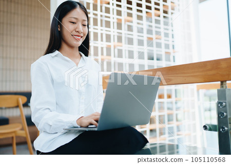 A young Asian self employed woman showing a smiling face and happiness while using a computer at a cafe shop. self-employed, freelance, relaxation 105110568