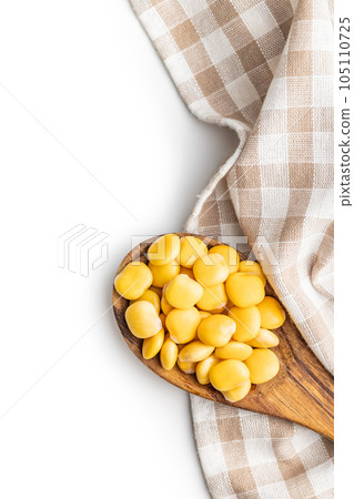 Lupini beans in brine. Pickled lupin in wooden spoon isolated on white background. 105110725