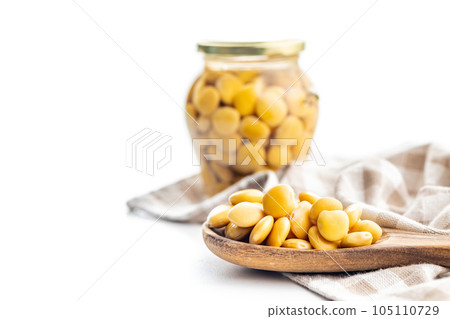 Lupini beans in brine. Pickled lupin in wooden spoon isolated on white background. 105110729