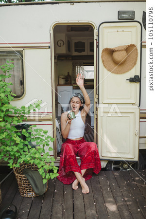 Happy hippie girl are having a good time with cup of tea in camper trailer. Holiday, vacation, trip concept. Happy hippie girl are having a good time with cup of tea in camper trailer. Holiday, vacation, trip concept. 105110798