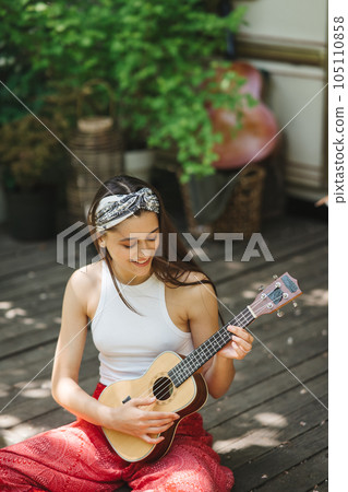 Happy hippie girl are having a good time with playing on guitar in camper trailer. Holiday, vacation, trip concept. Happy hippie girl are having a good time with playing on guitar in camper trailer. Holiday, vacation, trip concept. 105110858
