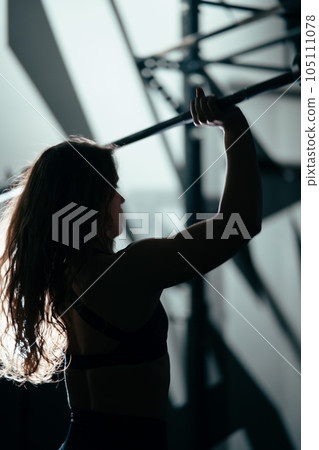 Athletic Beautiful Woman with barbell at gym 105111078