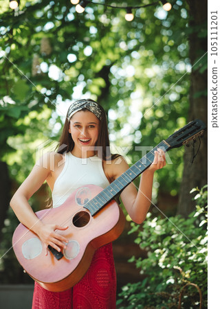 Happy hippie girl is having a good time with playing on guitar in camper trailer. Holiday, vacation, trip concept. Happy hippie girl is having a good time with playing on guitar in camper trailer. Holiday, vacation, trip concept. 105111201