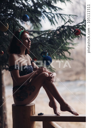 Beautiful girl in bikini sitting against of snow-covered trees in winter Beautiful girl in bikini sitting against of snow-covered trees in winter 105111511