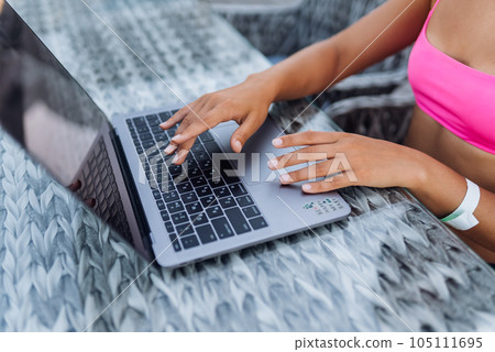 Cute young woman in swimsuit working on laptop sitting on terrace on the beach 105111695