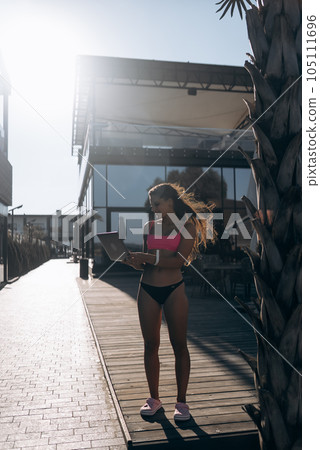 Cute young woman in swimsuit working on laptop on the beach Cute young woman in swimsuit working on laptop on the beach 105111696