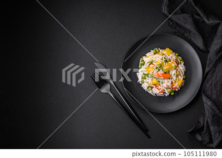 Delicious fresh white boiled rice with vegetables carrots, peppers and asparagus beans on a ceramic plate 105111980