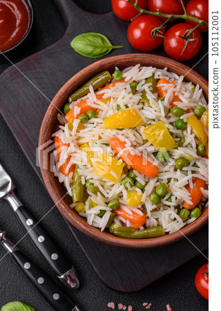 Delicious fresh white boiled rice with vegetables carrots, peppers and asparagus beans on a ceramic plate 105112001