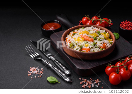 Delicious fresh white boiled rice with vegetables carrots, peppers and asparagus beans on a ceramic plate 105112002
