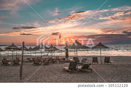 Sunshade beach umbrellas with sunset sky and sea background. Sarande, Albania Sunshade beach umbrellas with sunset sky and sea background. Sarande, Albania 105112120
