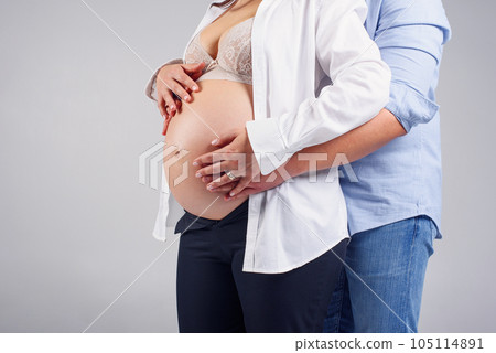 Pregnant woman and her husband holding hands together on her belly. Happy pregnancy concept. 105114891