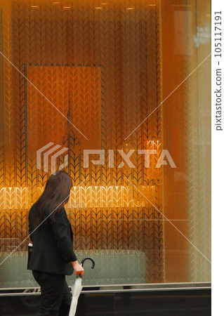 A woman passing in front of a shop window A woman passing in front of a shop window 105117191