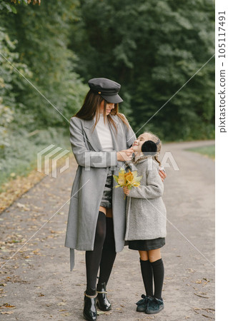 Fashionable mother with daughter. People walks outside. Woman in a gray coat. 105117491