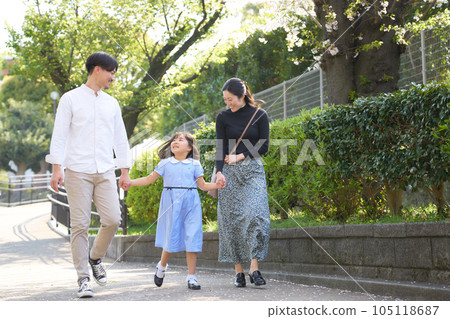 A family of three walking hand in hand while laughing 105118687