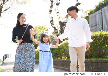 一個女孩和她的父母牽著手笑著走路 105118711