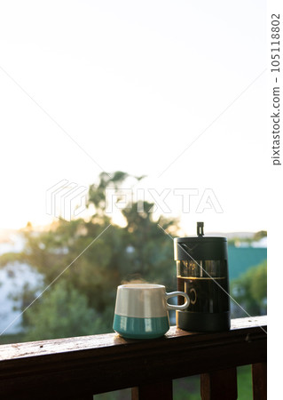Vertical image of close up of coffee press and mug of fresh coffee at balcony on sunny day 105118802