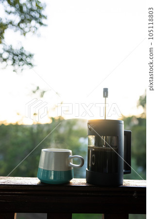 Vertical image of close up of coffee press and mug of fresh coffee at balcony on sunny day 105118803