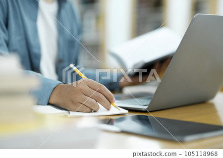 Young university student using laptop for online learning, searching and learning at library. 105118968