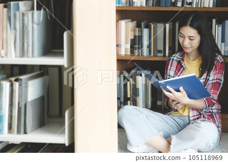 University students reading books in library for research. 105118969