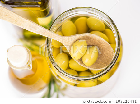Close up green olives in a wooden spoon and a bottle of olive and 105120481