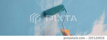 Painter paints wall blue color with roller. 105120916