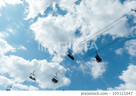 Mountain four-seater chairlift on the background of a blue cloud sky. 105121047