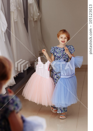 A small girl or client chooses a dress in front of a mirror. A small girl or client chooses a dress in front of a mirror. 105123013
