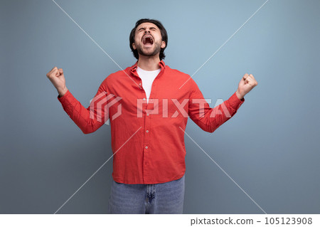 a handsome young brunette man in a red shirt tells interesting news a handsome young brunette man in a red shirt tells interesting news 105123908