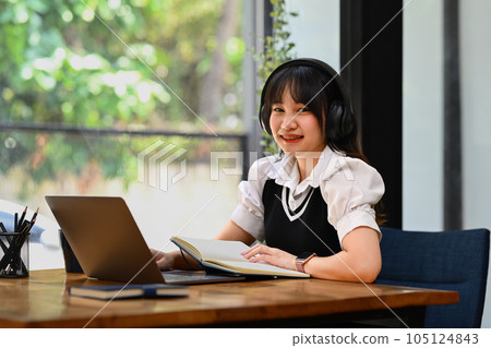Online education, e-learning. Happy Asian young woman wearing headphone, studying remotely, using a laptop 105124843