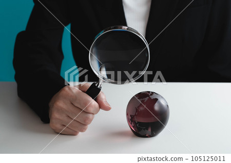 Woman looking at a globe with a magnifying glass 105125011