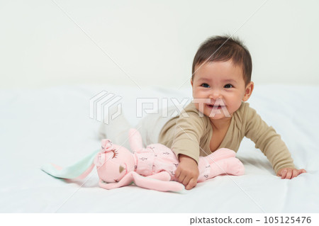 infant baby playing doll on bed infant baby playing doll on bed 105125476