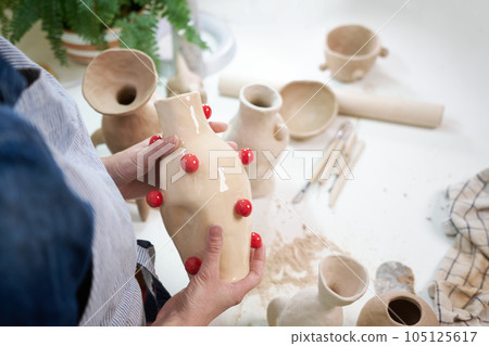 woman sculptor holding ceramic vase in artistic studio woman sculptor holding ceramic vase in artistic studio 105125617