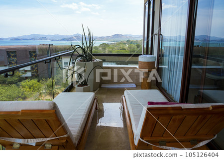 Two deckchairs in hotel room balcony by swimming pool, seascape and mountain in the background at Costa Rica Two deckchairs in hotel room balcony by swimming pool, seascape and mountain in the background at Costa Rica 105126404
