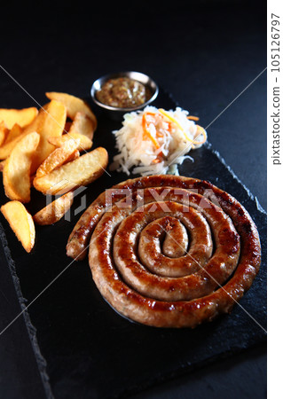 Bavarian beer appetizer. Smoked sausages on a wooden board. The concept of German cuisine. Meat sausages with sauce. 105126797