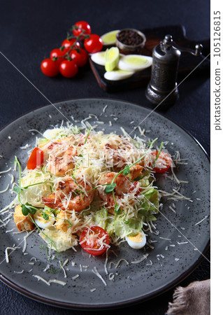 Shrimp salad. Caesar salad with shrimp.On a dark background. Without people. Vertical photo. 105126815