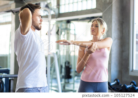 Sport men and women doing stretch before exercise in fitness gym Sport men and women doing stretch before exercise in fitness gym 105127524