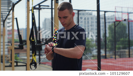 Young man checking incoming notification on smart watch. Animation of social media icons. Global social media and digital interface concept. Young man checking incoming notification on smart watch. Animation of social media icons. Global social media and digital interface concept. 105129607