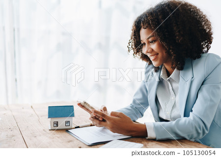 Real estate agent, African American businesswoman Africans use smartphone and calculators to offer mortgages to their clients. Home mortgage and insurance finance concepts. 105130054