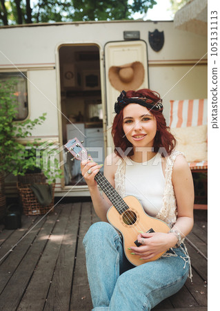 Happy hippie girl is having a good time with playing on guitar in camper trailer. Holiday, vacation, trip concept. Happy hippie girl is having a good time with playing on guitar in camper trailer. Holiday, vacation, trip concept. 105131113