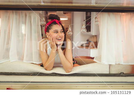 Happy hippie girl is having a good time in a camper trailer. Holiday, vacation, trip concept. Happy hippie girl is having a good time in a camper trailer. Holiday, vacation, trip concept. 105131129