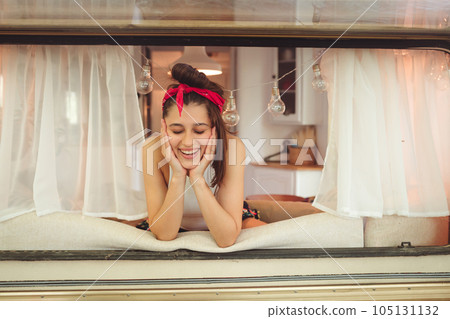 Happy hippie girl is having a good time in a camper trailer. Holiday, vacation, trip concept. Happy hippie girl is having a good time in a camper trailer. Holiday, vacation, trip concept. 105131132