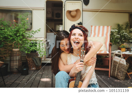 Happy hippie friends are having a good time together with guitar in camper trailer. Holiday, vacation, trip concept. Happy hippie friends are having a good time together with guitar in camper trailer. Holiday, vacation, trip concept. 105131139